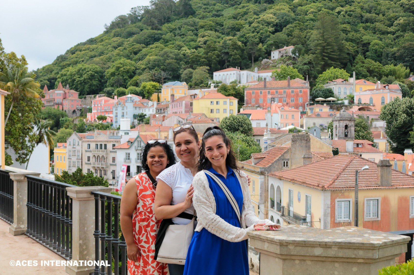 Three Educators Field Study group members take a picture in front of a coastal town in Portugal.